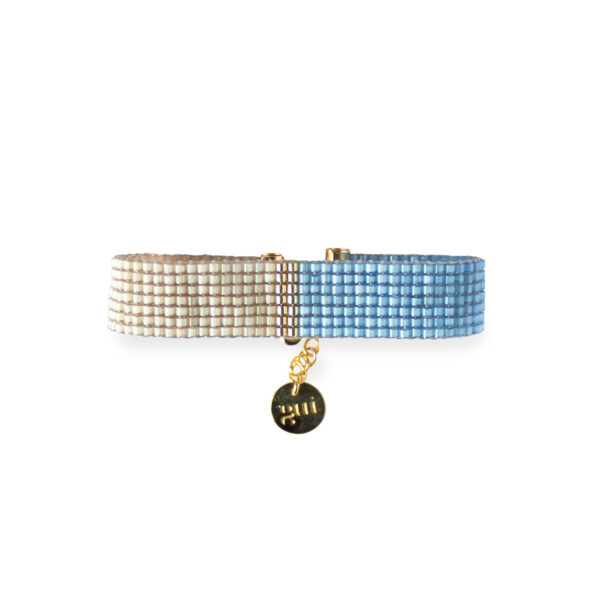 Elegant blue and beige beaded bracelet with a gold charm on a white background.