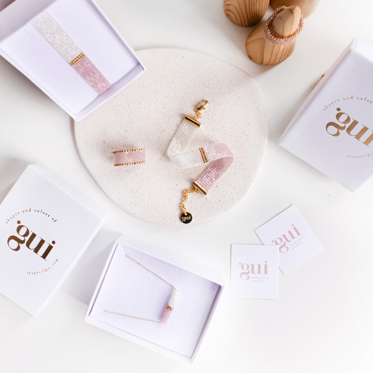 Elegant jewelry pieces displayed on a marble plate with branded packaging around.